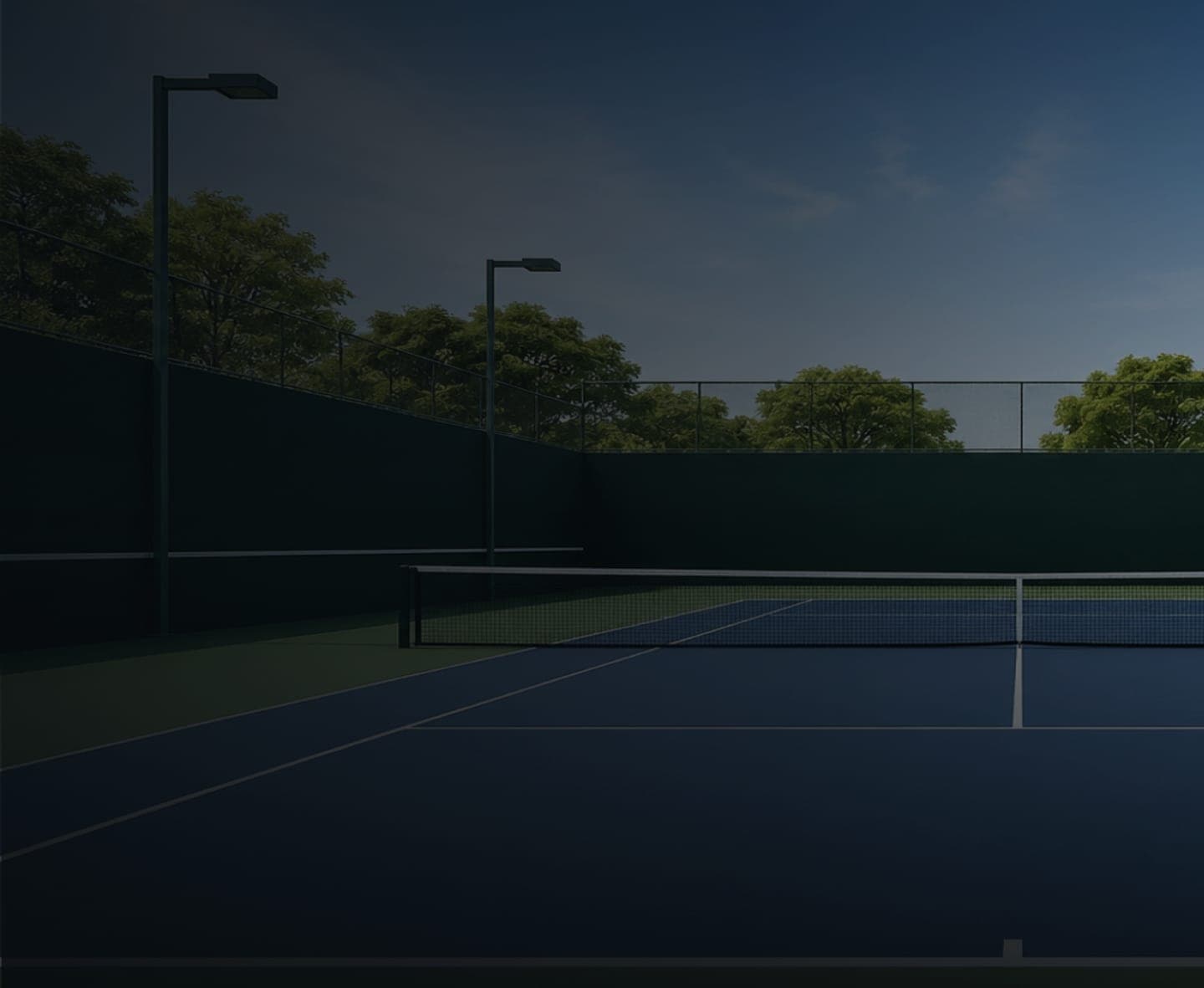 Empty floodlit tennis court at dusk
